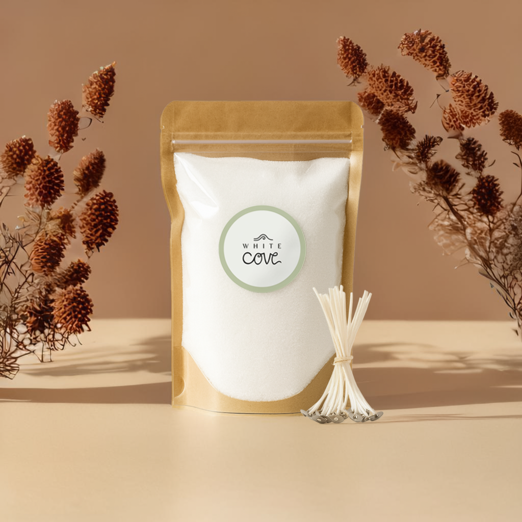 White eco-friendly Pearled Wax Candle Sand in a brown Kraft packaging with 'White Cove' label, surrounded by dried plants on a beige background, with white cotton candle wicks