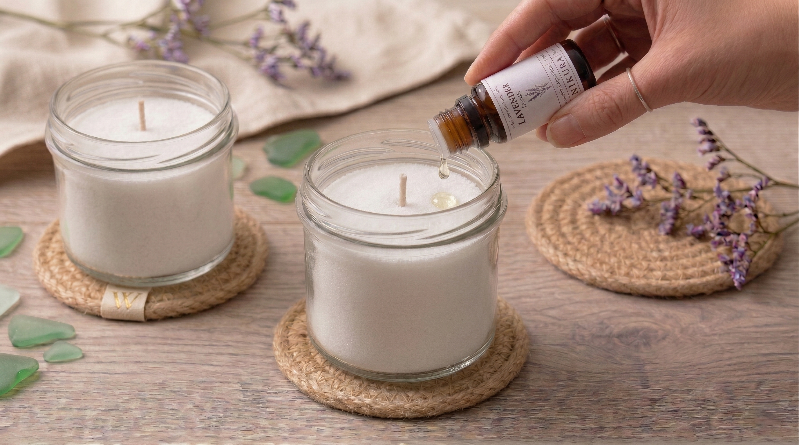 Scenting White Cove plant-based candle sand pearled wax with lavender essential oil. A coastal-themed DIY candle setup with sea glass and rustic coasters on a wooden table. Hand-packed in Dorset, UK