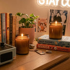 Creating a cozy evening aesthetic with White Cove UK plant-based candle sand. This lifestyle shot demonstrates how to upcycle amber glass jars into custom refillable candles, styled on a wooden dresser next to a vintage turntable and novels