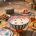 Vibrant outdoor summer entertaining aesthetic featuring a massive multi-wick centerpiece made with White Cove UK plant-based candle sand. This lifestyle shot demonstrates how to upcycle large bowls for al fresco dining, styled on a patio table with festive party food and festoon lights
