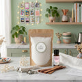 Sustainable candle making kit by White Cove UK styled in an aesthetic modern kitchen. This lifestyle shot showcases the complete plant-based candle sand ecosystem, including dual wick options and Relax & Unwind fragrance oil, arranged on marble with fresh botanicals and cozy room accessories