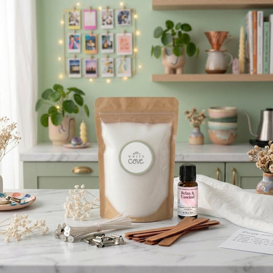 Sustainable candle making kit by White Cove UK styled in an aesthetic modern kitchen. This lifestyle shot showcases the complete plant-based candle sand ecosystem, including dual wick options and Relax & Unwind fragrance oil, arranged on marble with fresh botanicals and cozy room accessories